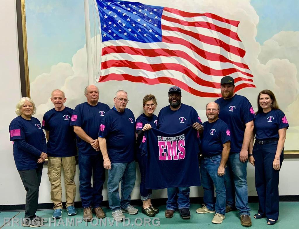 October 25, 2023. As Breast Cancer Awareness Month wraps up, the Bridgehampton Fire District, Department Chiefs and an EMS Company captain all wore breast cancer awareness shirts at the district meeting Wednesday night. The shirts have been worn by Bridgehampton EMS personnel all month as a sign of support for a member recently diagnosed with breast cancer, as well as so many in our department and community who have been affected.
Pictured from left, EMS 1st Asst. Captain Stacy Ludlow, Commissioner Jeffrey White, Commissioner Chairman Robert Comfort, Commissioner John O’Brien, Commissioner Elizabeth Whelan Kotz, Chief Nick Hemby, 1st Asst. Chief Thomas Federico, 2nd Asst. Chief Dillon Berkoski and District Manager Pamela Balserus.